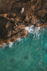 A couple lays on a cliffside on Oahu during their engagement session. As captured by a drone.