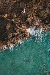 A couple lays on a cliffside on Oahu during their engagement session. As captured by a drone.