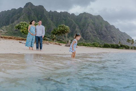 a small child explores the beach with her parent at Kualoa during their maternity family photo session.