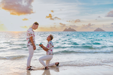 LGBTQ+ couple proposal at Lanikai Beach during sunrise with golden light and ocean waves