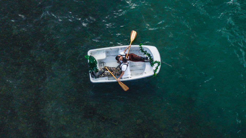 A couple kiss in a rowboat as photographed from the sky