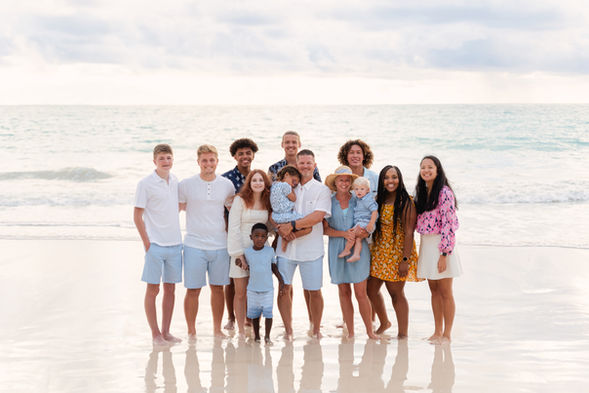 A large family embraces on he beach during their sunrise family photoshoot.