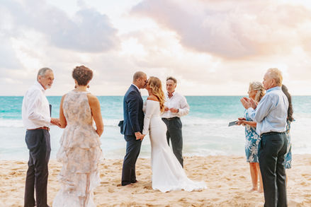 A couple kisses at their oahu Elopement on the beach at sunrise