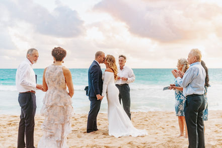 A couple kisses at their oahu Elopement on the beach at sunrise