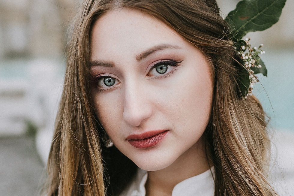 Close-up portrait of bride in lace gown with natural makeup and floral hairpiece, Rome.
