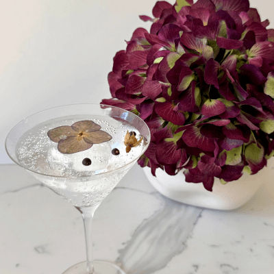 Gin & Tonic in a cocktail glass with flower garnish