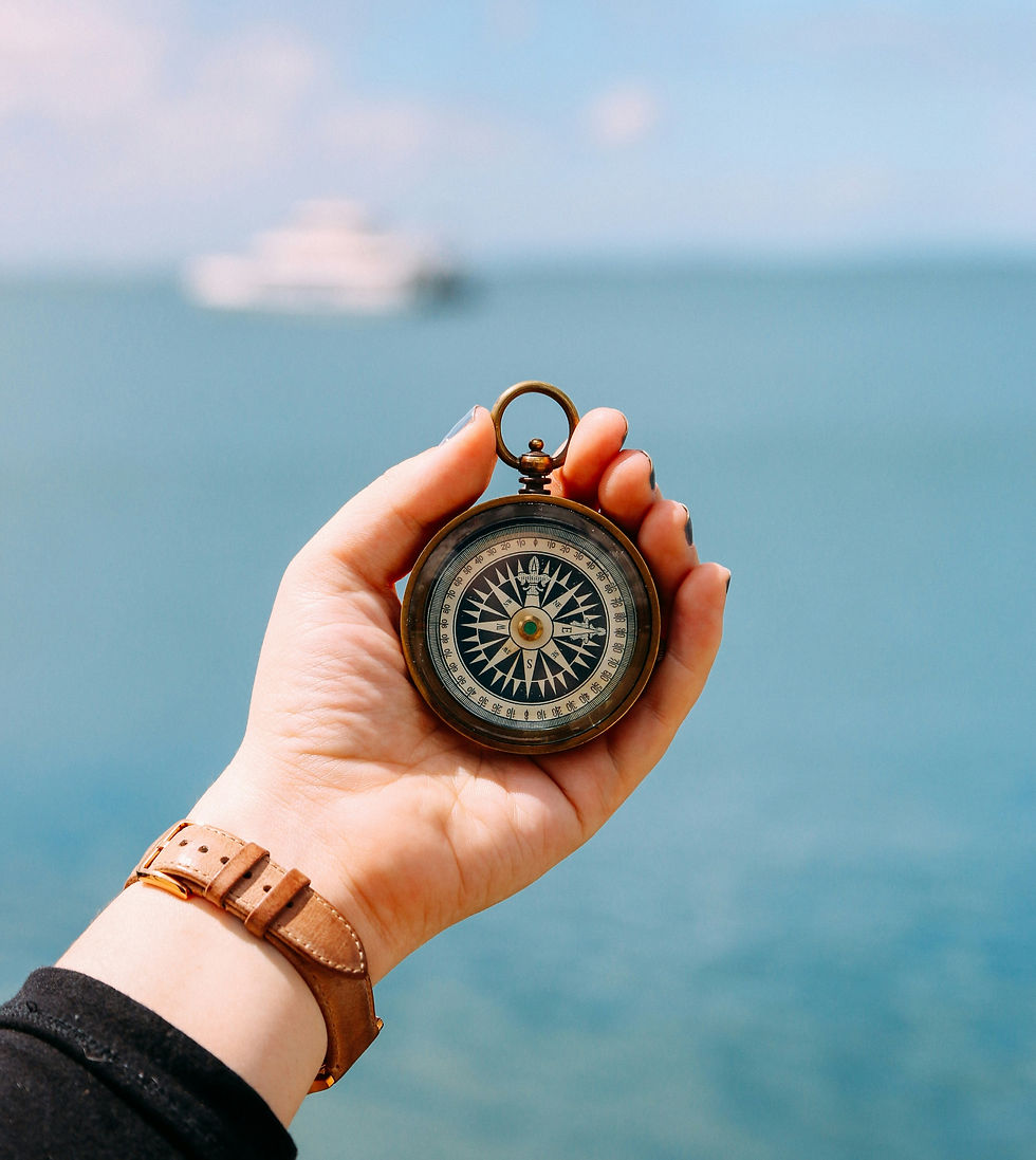 Eine Frau hält einen Kompass in der Hand Im Hintergrund sieht man ein Schiff auf dem Meer