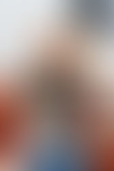 Hazel Turner from Well-Designed wearing a dark blouse laughs while talking on the phone, sitting on a rust-colored sofa with a lamp and window in the background.