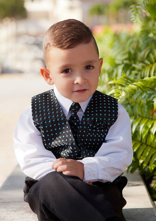 Young boy dressed formally and seated outdoors during a natural family photography session in South Florida