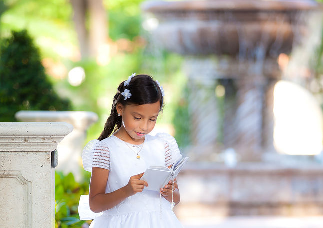 Communion portrait of girl reading a prayer book outdoors in South Florida