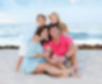 Portrait of a happy family smiling together on a sandy beach in Fort Lauderdale FL