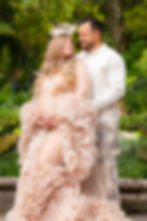 Maternity portrait of an expectant couple posing lovingly outdoors in a lush garden setting in Vizcaya Gardens, Miami FL.