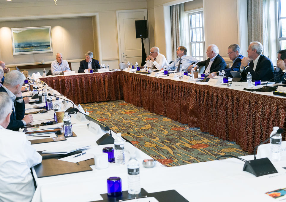 Boardroom-style corporate meeting with executives seated around U-shaped conference table during formal business summit, corporate event photography PhotographybyLuigi - Orlando FL