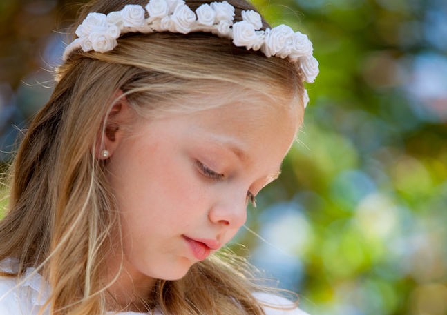 Close-up portrait of a young girl wearing a floral headband during an communion outdoor photography session in South Florida.