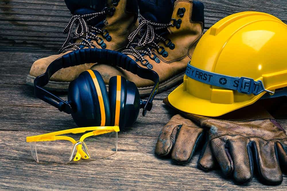 Personal protective equipment including helmets, gloves, safety glasses, vests, and masks arranged together without people.