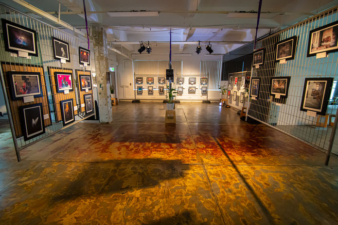 Wide-angle photograph of a modern art gallery interior with framed artwork and warm lighting, captured by Sydney Commercial Photography.