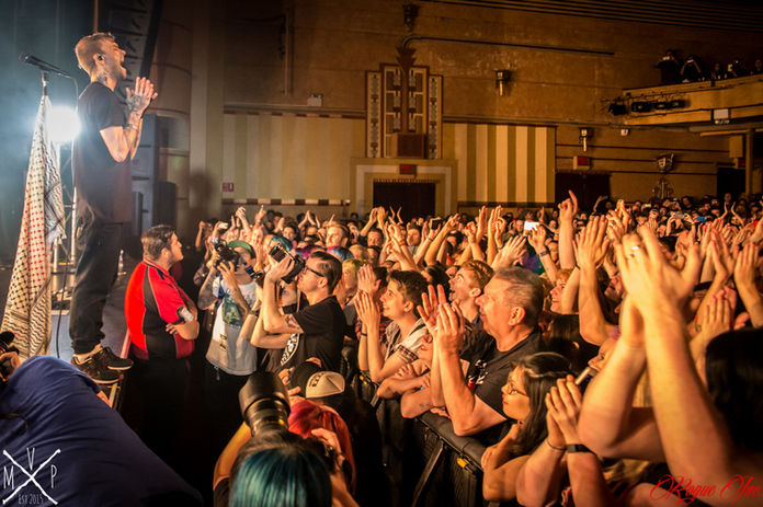 Singer on stage engaging with a cheering crowd under golden concert lighting, captured by Sydney Commercial Photography