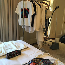 Off-White garment on a hotel bed beside a sewing machine after tailoring by Princess Faraj