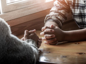 Couple praying together at the table.