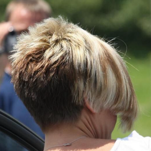 Back view of a sharply stacked blonde bob with a dramatic wedge shape and dark underlayer.