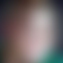 Person with a shaved head and a few thin baby bangs hanging down across the forehead.