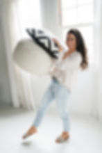 Home designer carrying large fluffy pillows.