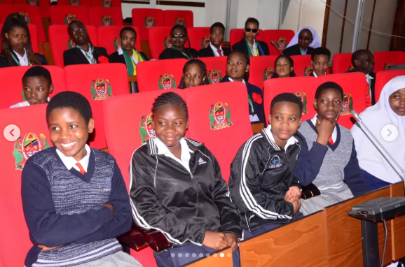 Eye-level view of students listening during an educational tour outside a public building in Dodoma.