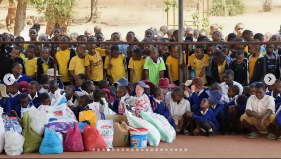 Wide-angle view of pupils preparing donation items in a school courtyard.