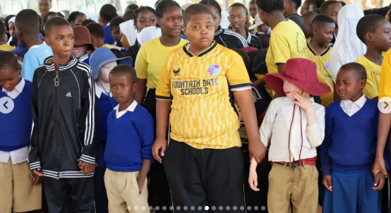 Wide-angle view of pupils and a teacher standing outside a community centre.