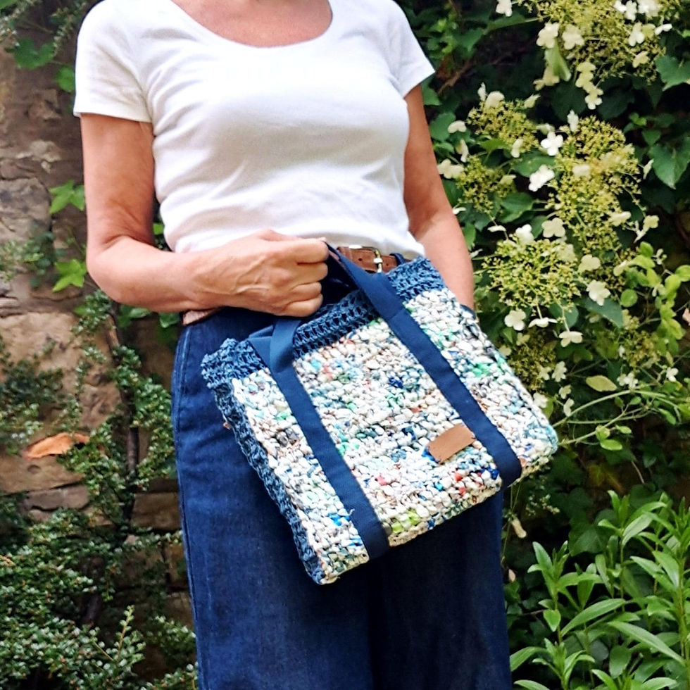 Structured handbag from recycled plastic bags & raffia twine. Mainly white with blue. Webbing handles. With model holding