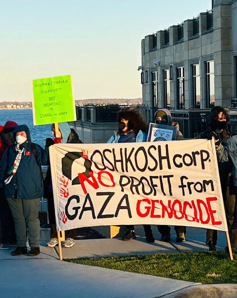 People holding large signs that says "Oshkosh corp no profit from Gaza genocide"