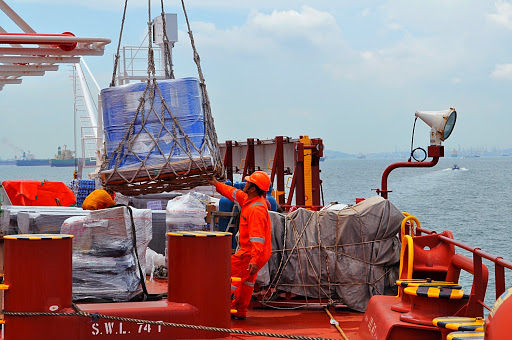 Seaman overseeing the crane operation as supplies are loaded onto the ship.