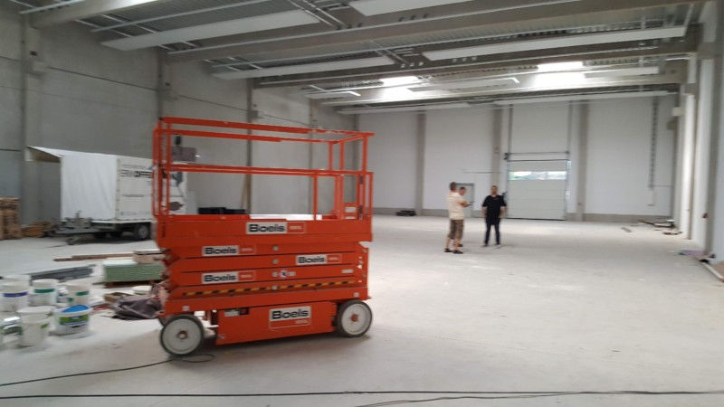 Bühnenarbeitsbühne in leerer Lagerhalle mit zwei Männern