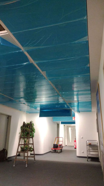 Bürogebäude-Decke mit türkisfarbener Verkleidung, Leiter und Handwagen im Flur
