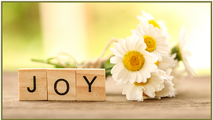 The word "JOY" on scrabble pieces with daisies