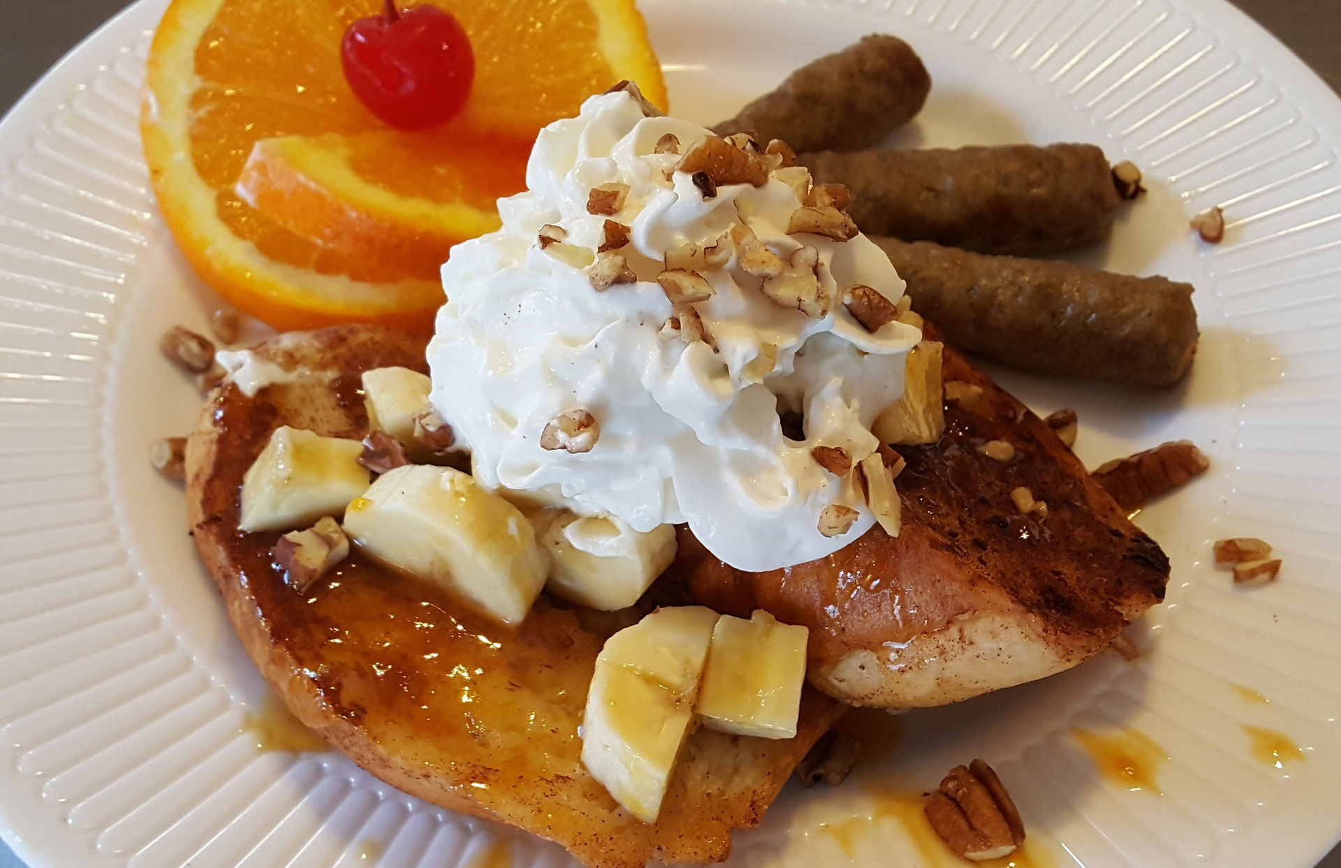 French Toast topped with Apricot, Almond, Orange glaze served with sausages links