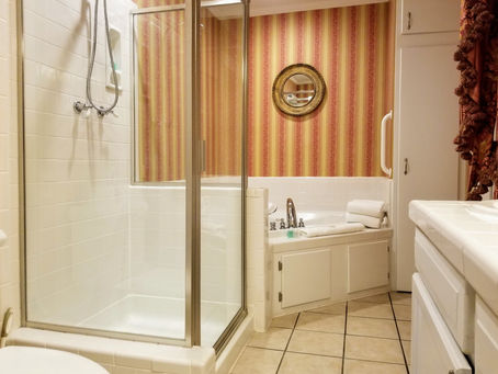 The spacious Garden Room bath suite featuring a large two-person corner Jacuzzi tub and a separate walk-in shower, a key luxury amenity in our Boutique Natchitoches B&B Experience.