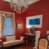 The grand red entrance hall and historic staircase at the Judge Porter House in Natchitoches.