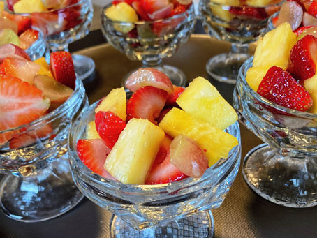 A breakfast tray loaded with pedestal crystal bowls full of fresh strawberries, pineapple, and red grapes being readied to serve guests at an outstanding historic bed and breakfast.