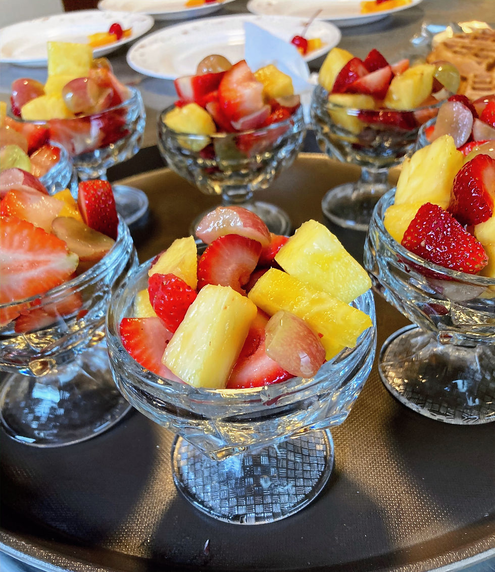 : A breakfast tray loaded with pedestal crystal bowls full of fresh strawberries, pineapple, and red grapes being readied to serve guests at an outstanding historic bed and breakfast.