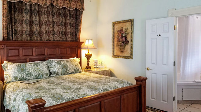 King-size wooden bed with the private bathroom entrance visible in the Garden Guest Room.