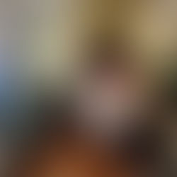 Ornate bedroom with floral-patterned bedspread, wooden furniture, and striped wallpaper. Soft lighting creates a cozy, vintage ambiance.