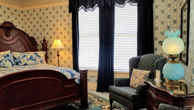 Carved king bed and wingback chair in the spacious Blue Guest Room.