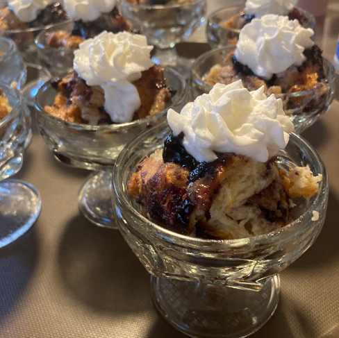 Innkeeper Sherry smiling while serving a tray of gourmet breakfast fruit sundaes in traditional glass sundae dishes at the premier historic bed and breakfast.