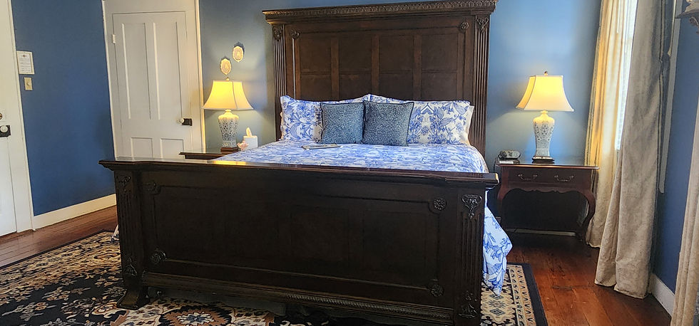 Wooden bed with blue floral bedding, flanked by two lamps on nightstands, in a cozy room with blue walls and a patterned rug.