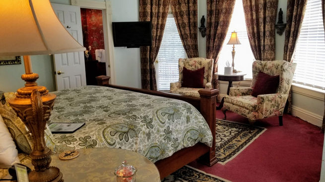 Wide view of the Garden Guest Room showing the king bed, bathroom door and draped door to the second-story gallery.