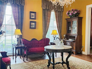 Historic front parlor at the Andrew Morris House Bed and Breakfast in Natchitoches, Louisiana, with antique furnishings and crystal chandeliers.