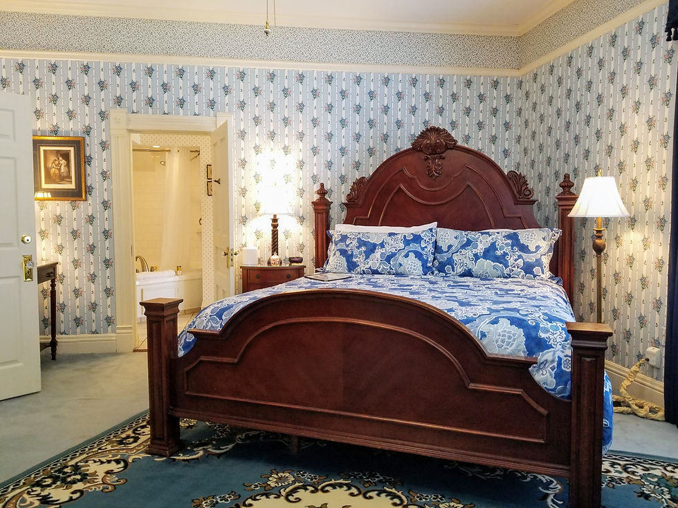 Spacious King sized bed in the Blue Room at the Queen Anne with premium linens and historic headboard.