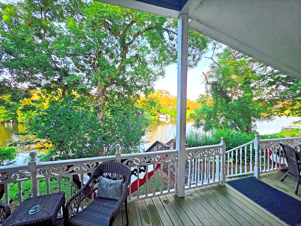 A wide, picturesque view of Cane River Lake looking out from the rear gallery porch of our luxury historic inn lodging, showcasing the green banks and calm water.