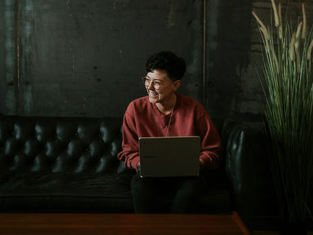 A founder sitting at their laptop smiling and working. Establishing credibility is important in your growing business.